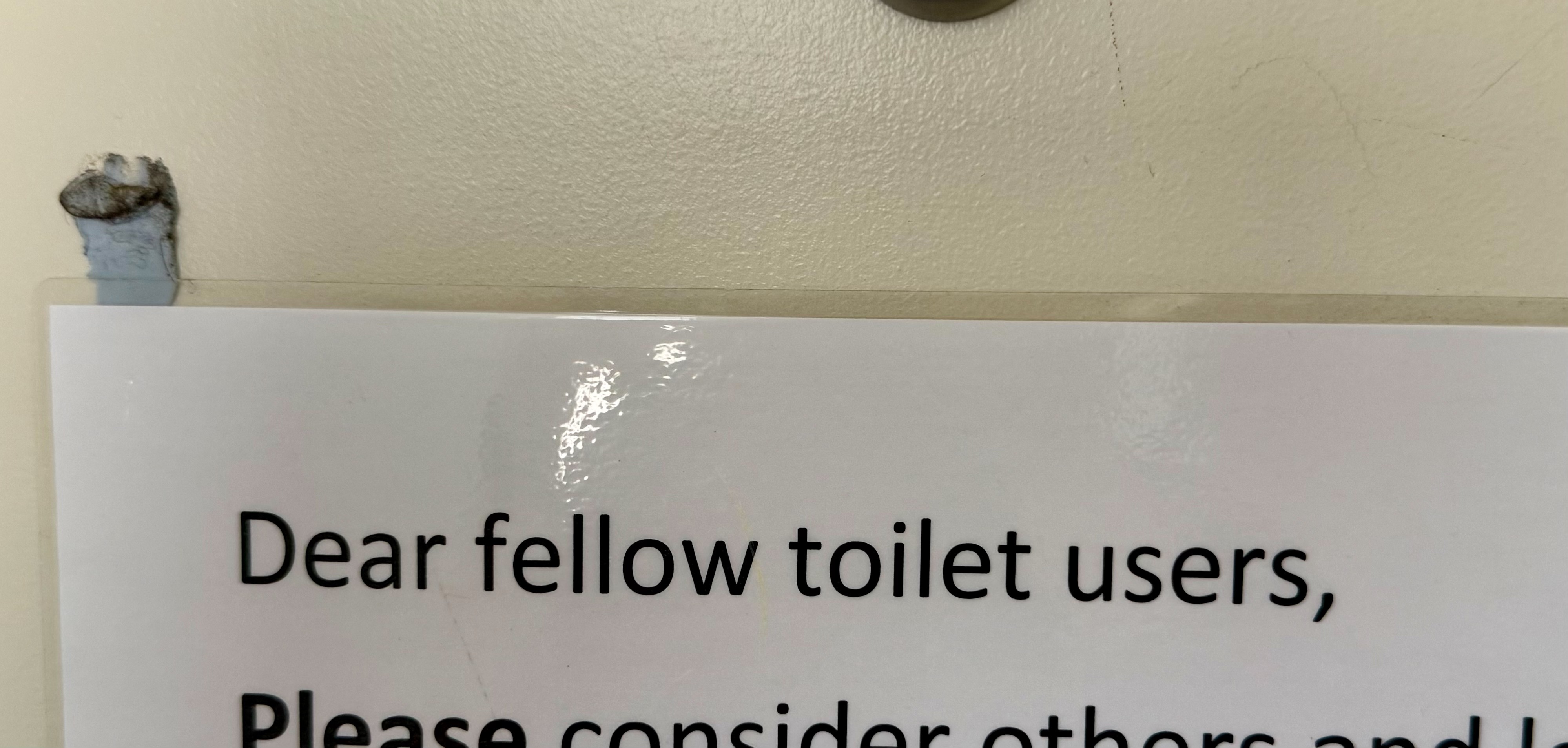 Laminated sign reads โDear fellow toilet users, -โ